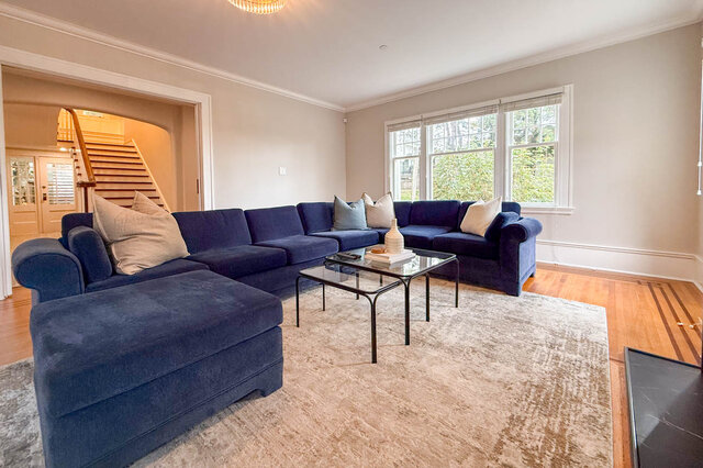 Living room with a bank of windows and a view out to the staircase and glass-paned doors. - North Vancouver