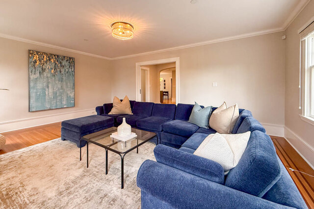 Living room under a crystal ceiling light, with crown moulding and a doorway to the hall. - North Vancouver