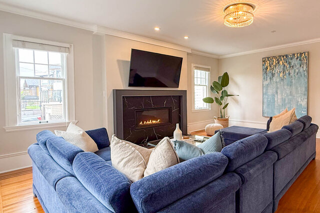 Living room with the fireplace, a crystal ceiling light and windows on two sides. - North Vancouver