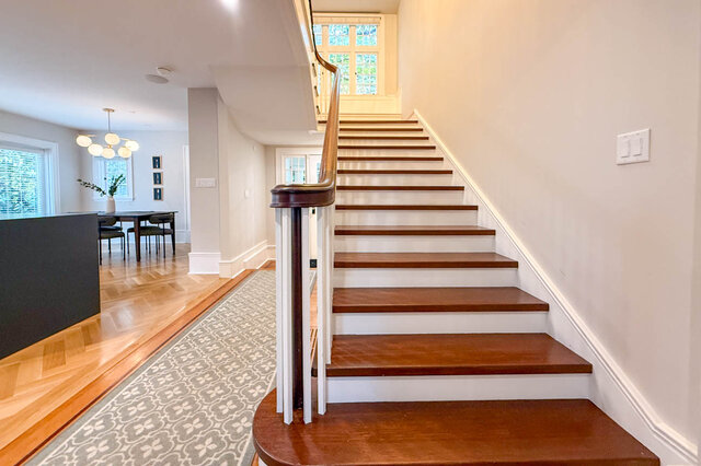 Staircase rising to a landing window, beside the dining area. - North Vancouver
