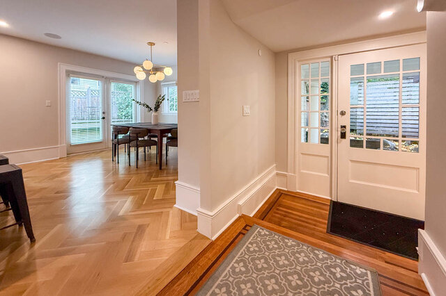 Dining area with French doors to the yard, a globe chandelier and herringbone floors, beside the side entry. - North Vancouver