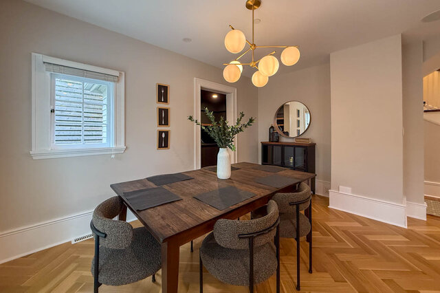 Dining area for eight under a globe chandelier, with herringbone floors. - North Vancouver