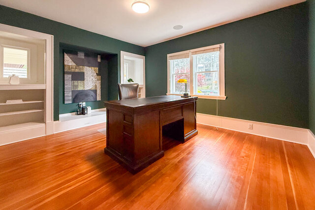 Library and home office with dark green walls, built-in shelving, a niche and windows to the street. - North Vancouver