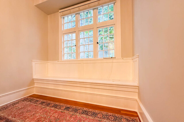 Built-in window seat under tall paned windows on the stair landing. - North Vancouver