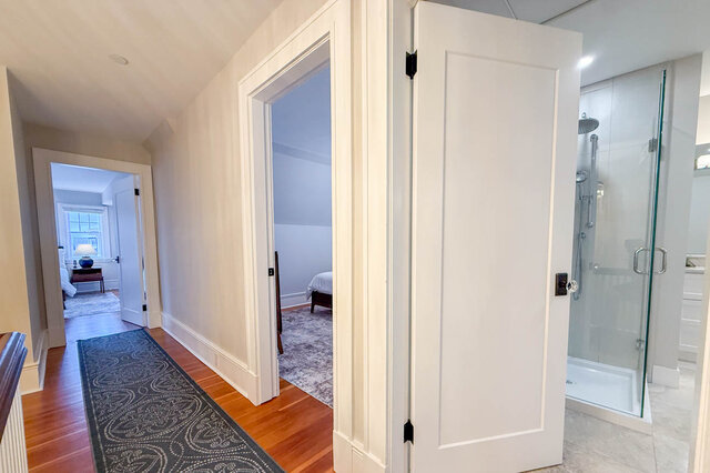 Upper hall with bedroom doors and a bathroom with a glass shower. - North Vancouver