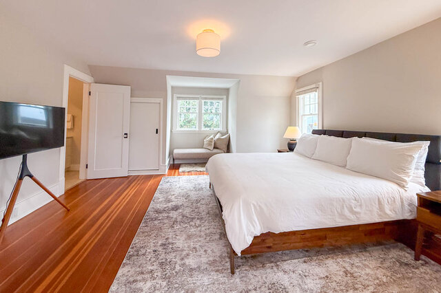Primary bedroom with doors to the ensuite and a closet, and a dormer window nook. - North Vancouver