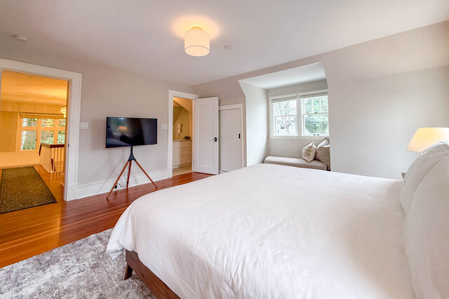Primary bedroom with the ensuite door, a dormer nook and the hall beyond. - North Vancouver