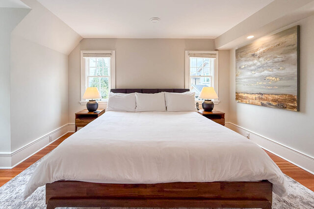 Primary bedroom with two windows and sloped ceilings. - North Vancouver
