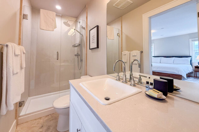 Ensuite with a glass shower, a rain shower head and a light quartz vanity. - North Vancouver