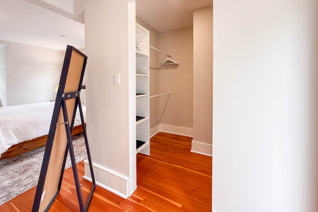 Primary walk-in closet with built-in shelving and hanging rods. - North Vancouver