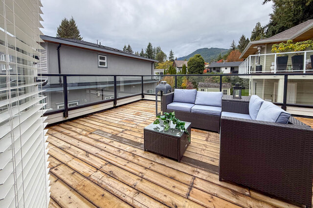 Private upper deck with a glass railing and a mountain view over the neighbourhood. - North Vancouver