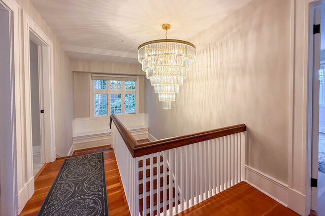 Upper landing with a tiered crystal chandelier and a window seat. - North Vancouver