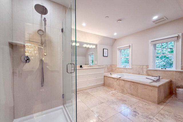 Main bathroom with a soaker tub, a separate glass shower, a long vanity and stone tile. - North Vancouver