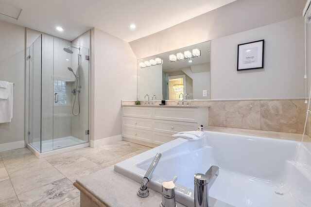 Main bathroom with a soaker tub, a glass walk-in shower and stone tile floors. - North Vancouver