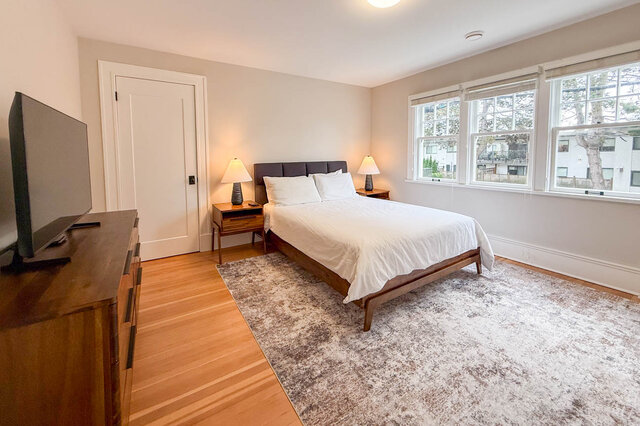 Third bedroom with a bank of three windows, a closet and hardwood floors. - North Vancouver